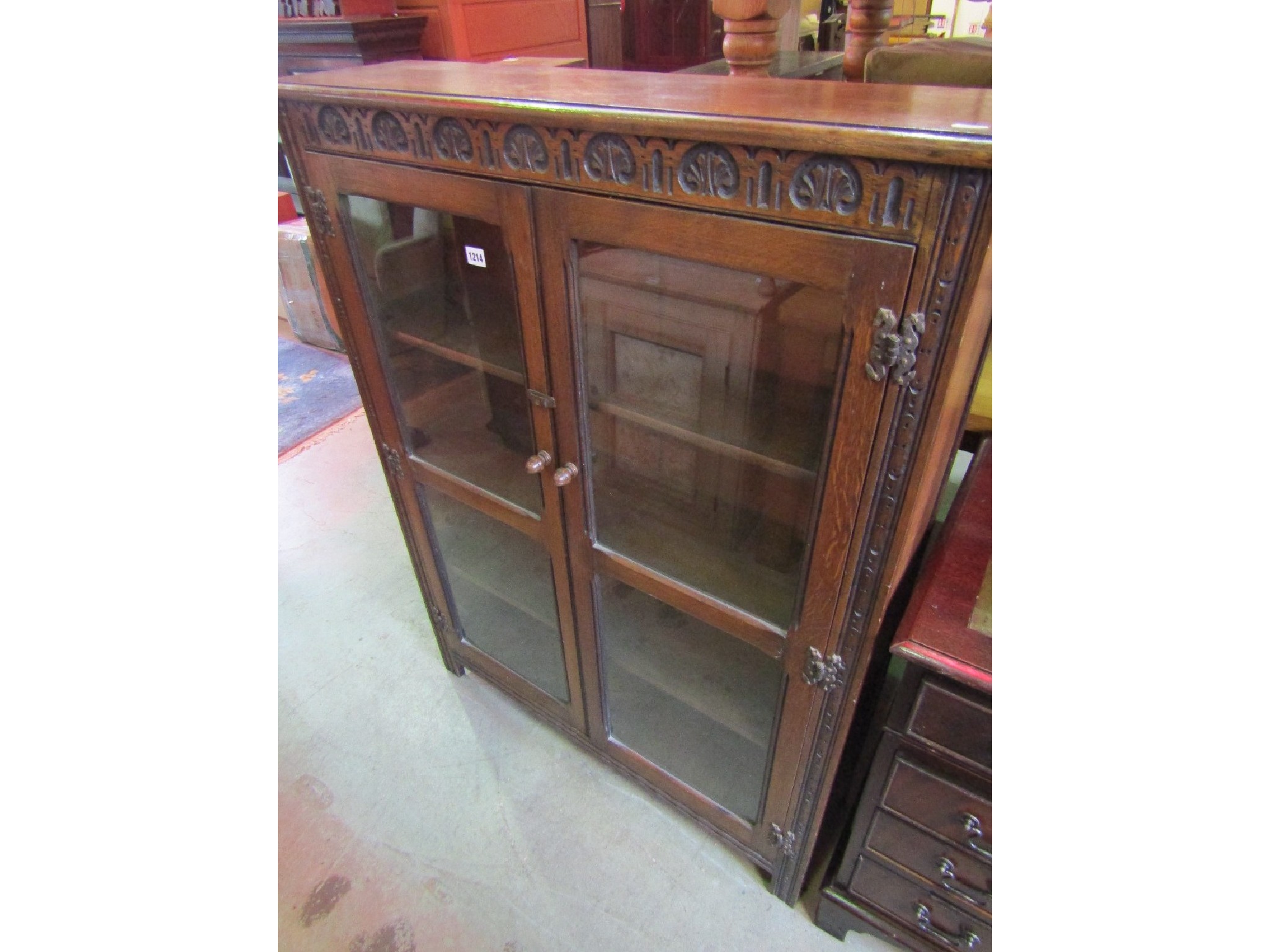 Appraisal: A slender freestanding oak side cabinet with carved frieze over