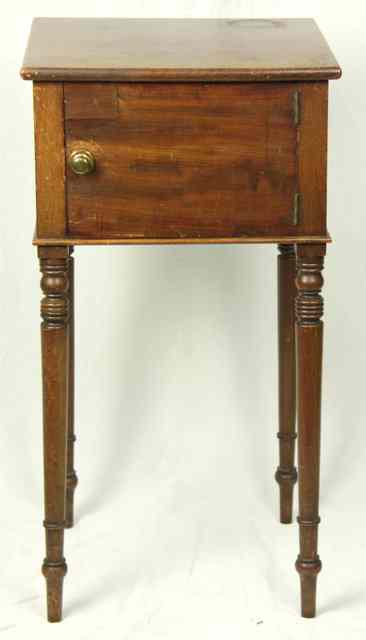 Appraisal: A mahogany bedside cupboard enclosed by a panel door on