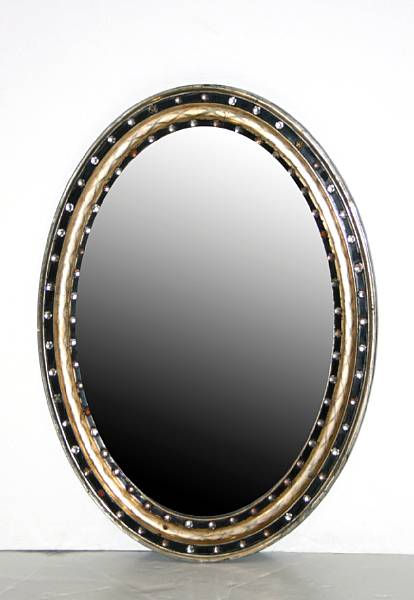 Appraisal: A partially ebonized and giltwood oval mirror inset with glass