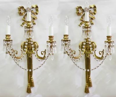 Appraisal: A pair of gilt metal three-branch wall sconces with ribbon