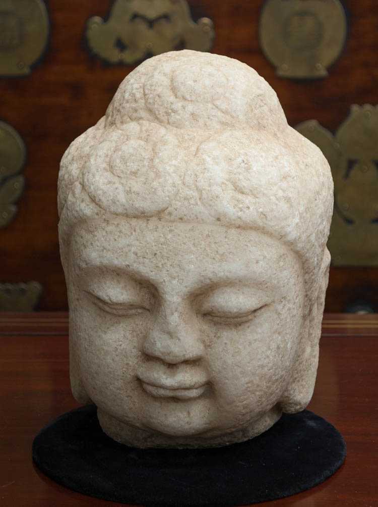 Appraisal: CARVED MARBLE BUDDHA HEAD with elongated ears and carved flattened