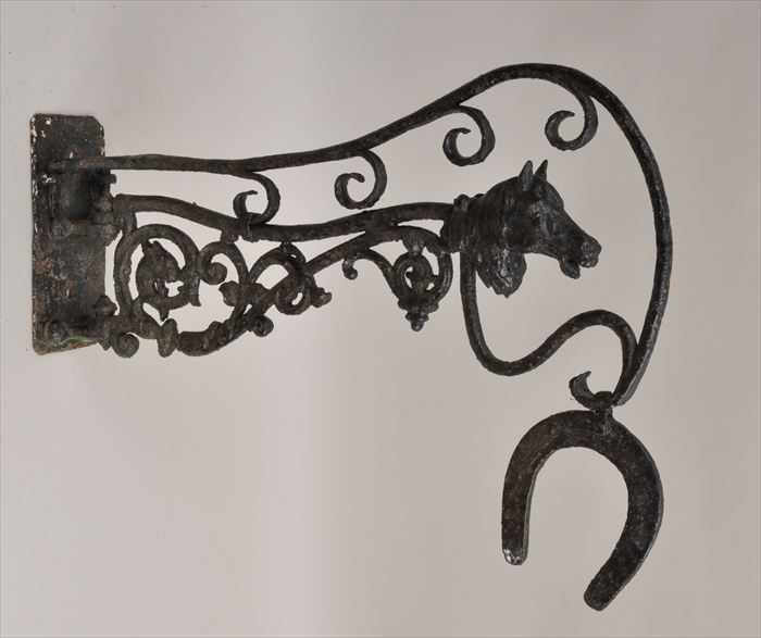 Appraisal: WROUGHT-IRON BRACKET The scrolling arm with horsehead above horseshoe pendant