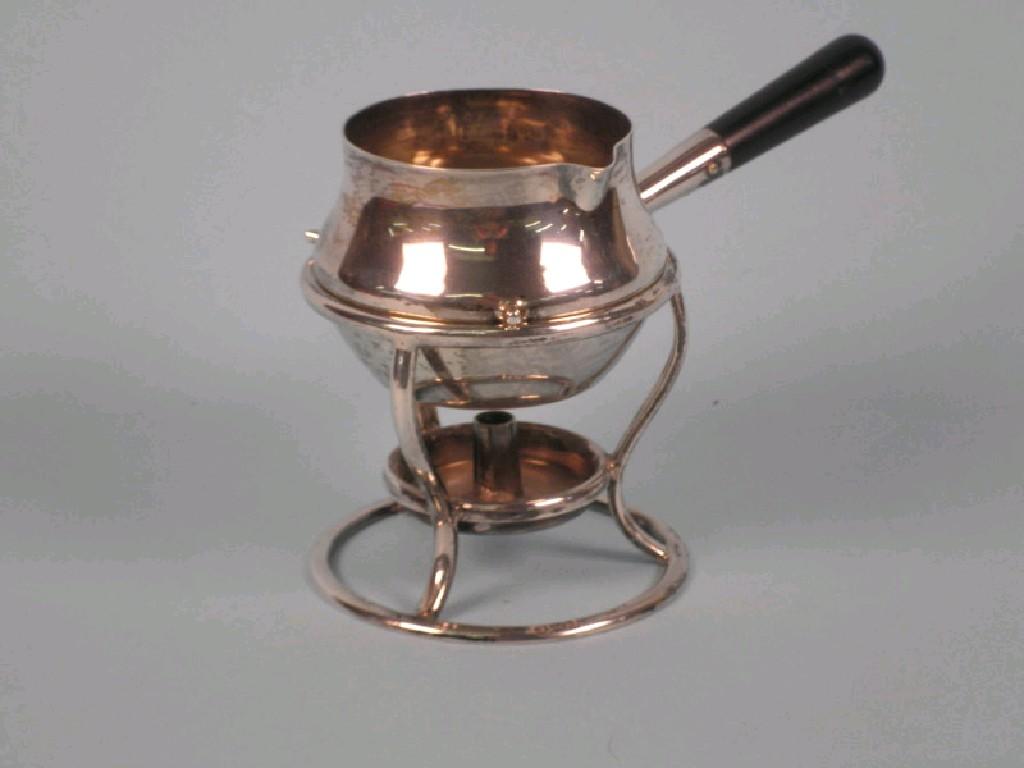 Appraisal: A silver brandy warmer with an ebonised handle and stand