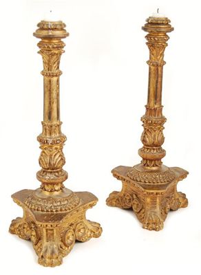 Appraisal: A pair of continental carved giltwood candlesticks with loaded lead