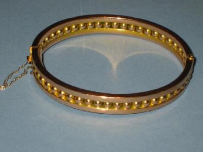 Appraisal: A GOLD BANGLE of hinged form moulded as a row