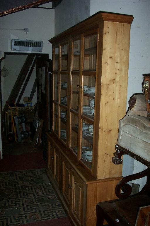 Appraisal: A substantial stripped and waxed pine bookcase cupboard the upper