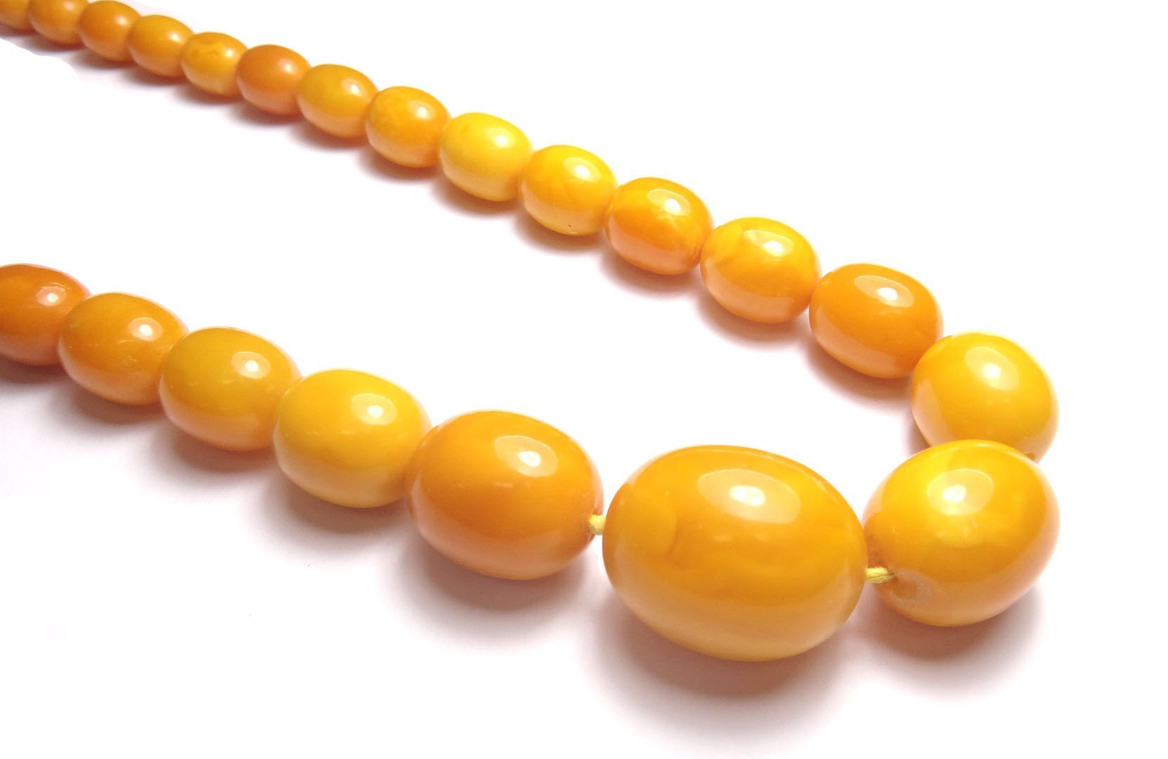 Appraisal: A single row necklace of oval mottled butterscotch coloured amber