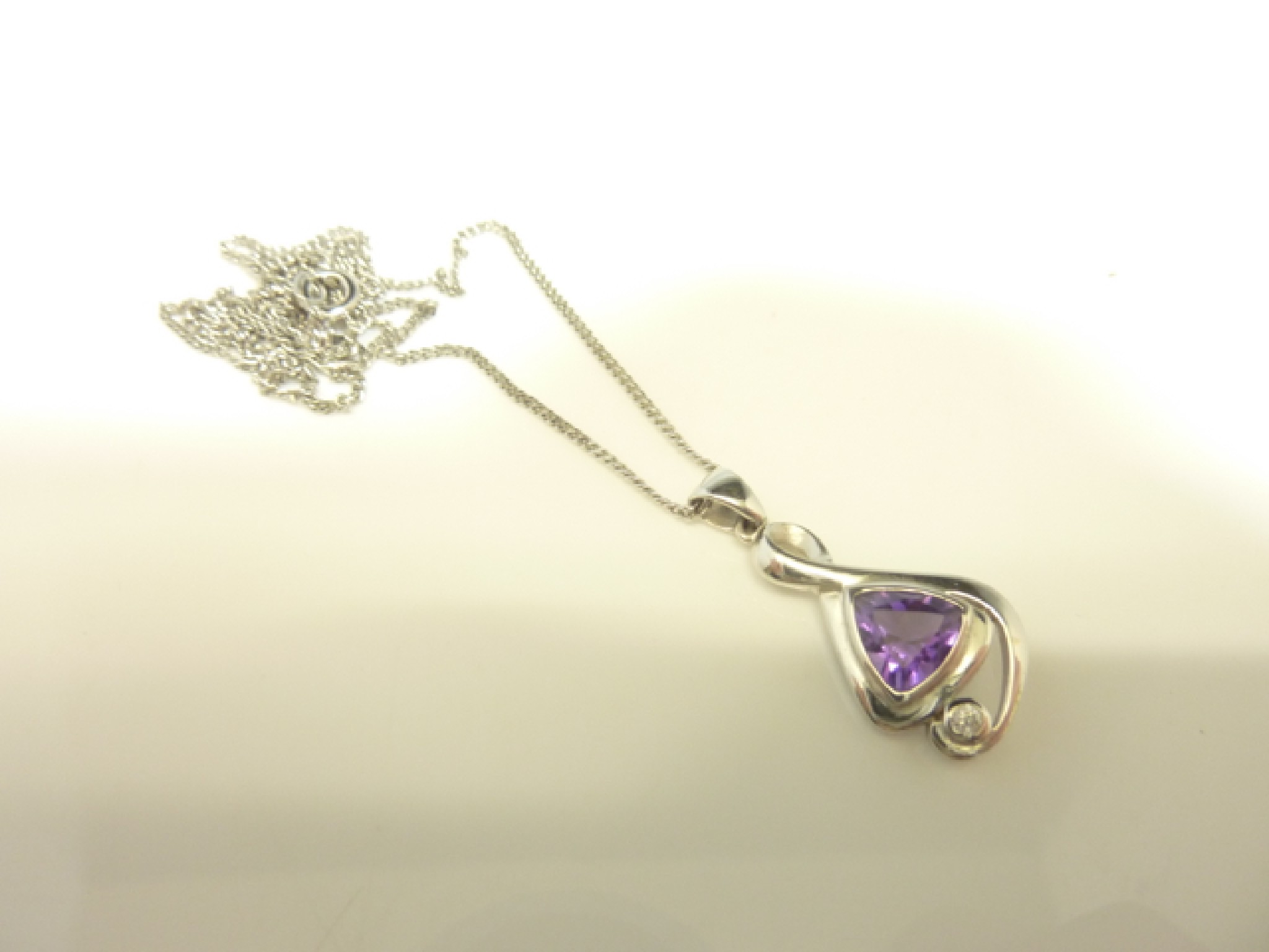 Appraisal: An amethyst and diamond pendant centred with a trilliant-cut untested