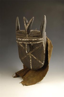 Appraisal: A Toma ebonised mask with applied metal bands and a