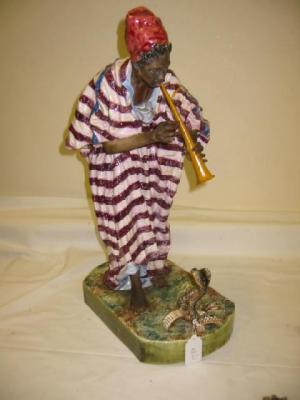 Appraisal: A GOLDSCHEIDER STYLE POTTERY FIGURE depicting a snake charmer wearing