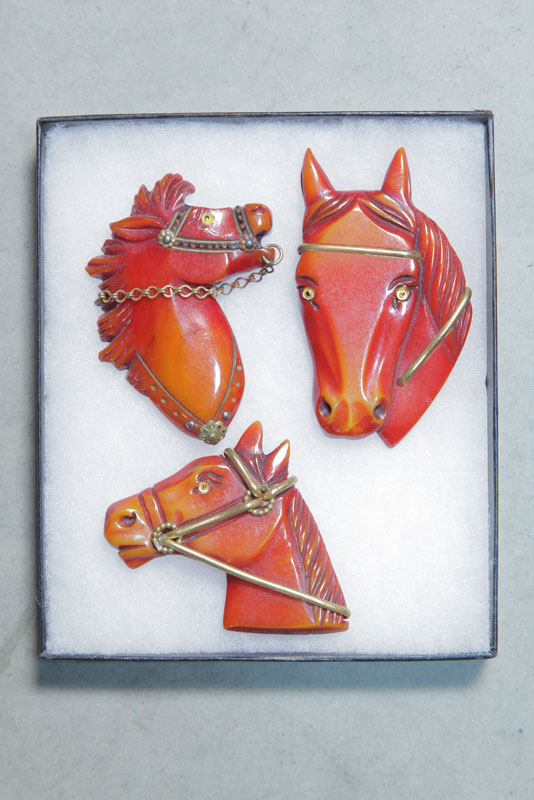 Appraisal: THREE BAKELITE HORSE PINS All red with brass accents ''h