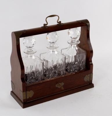 Appraisal: An Edwardian oak cased tantalus fitted three cut glass decanters