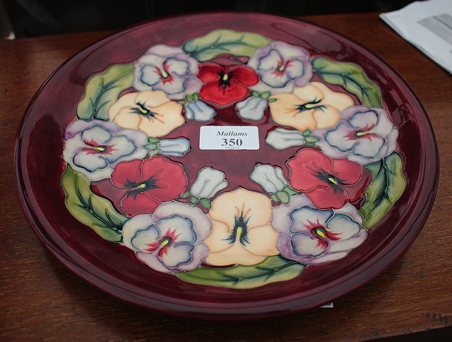 Appraisal: A BURGUNDY GROUND MOORCROFT PLATE decorated with pansies with impressed