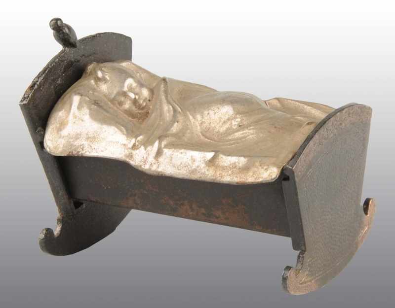 Appraisal: Pot Metal Baby in Cradle with Rosettes Still Bank Description