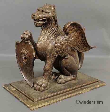 Appraisal: Finely carved architectural winged griffin holding a shield probably early