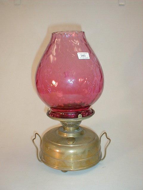 Appraisal: A Victorian brass foot warmer oil lamp with cranberry glass