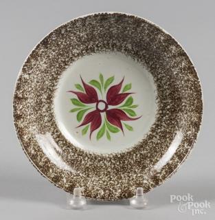 Appraisal: Brown spatter saucer with a four-petal flower decoration