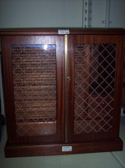 Appraisal: A coin cabinet the glazed panel doors enclosing a fitted