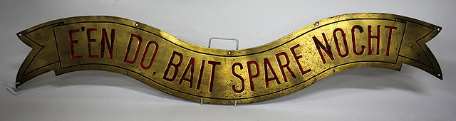 Appraisal: A BRASS RIBBON ENDED SIGN with red painted lettering 'E'en