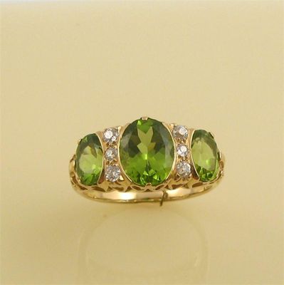 Appraisal: A peridot and diamond ring set with three graduated oval