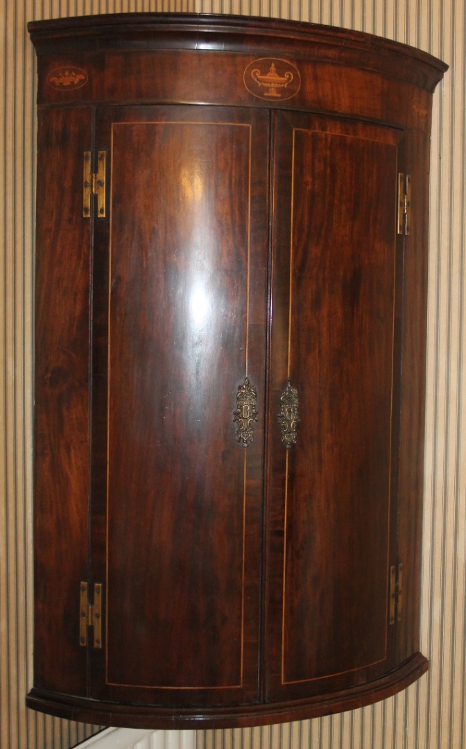 Appraisal: A Sheraton mahogany hanging bowfront corner cupboard with oval inlays