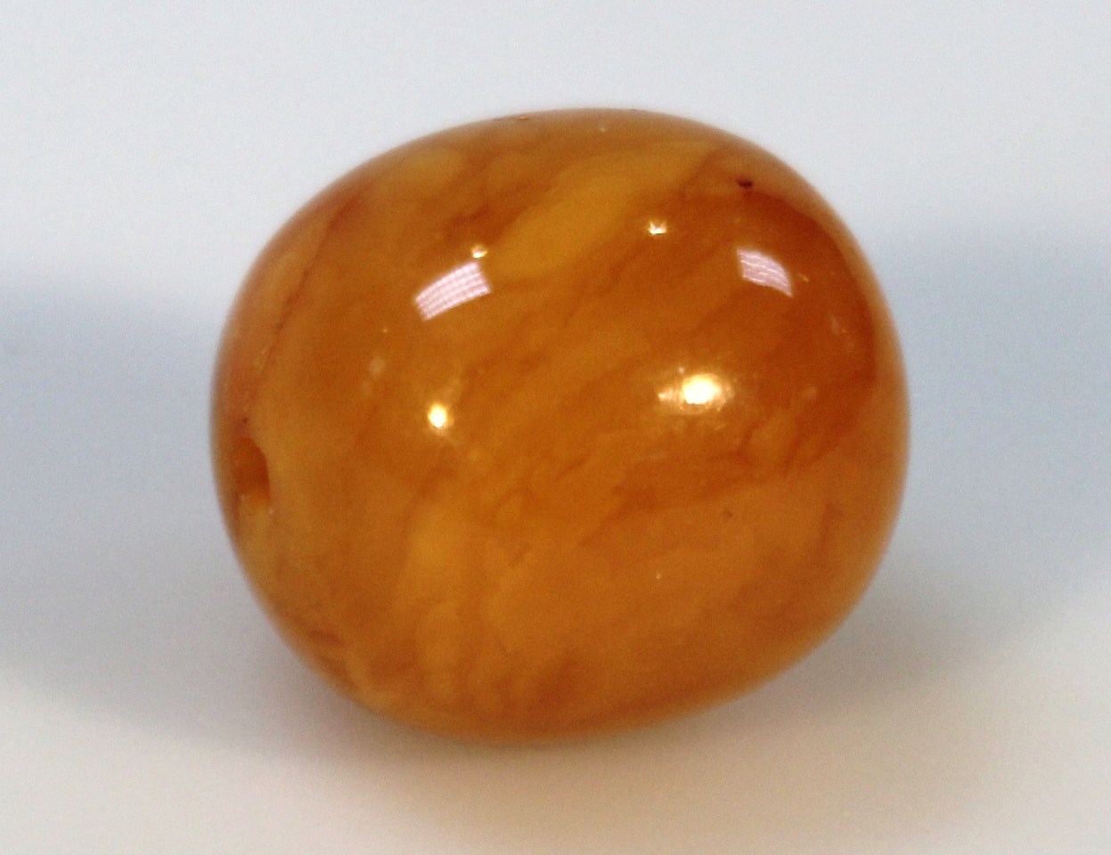 Appraisal: A butterscotch amber bead the compressed circular body drilled to