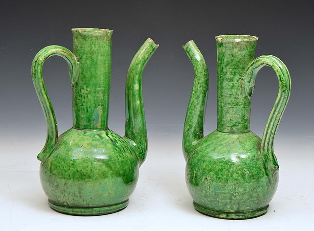 Appraisal: A PAIR OF TURKISH GREEN LEAD GLAZED STONEWARE SPOUTED EWERS