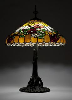 Appraisal: A patinated table lamp and leaded glass shade Early th