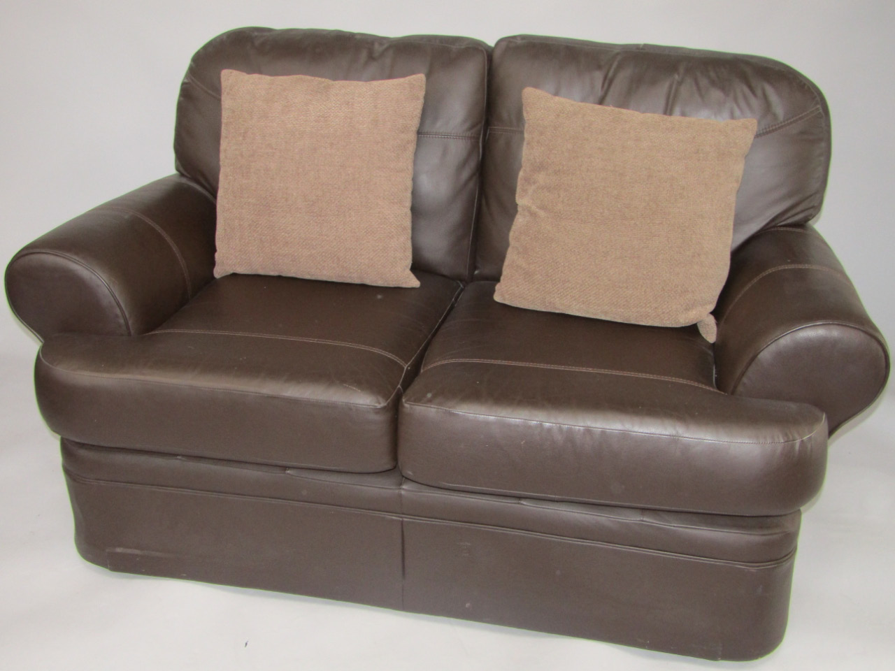 Appraisal: A leather two seater sofa with two loose cushions