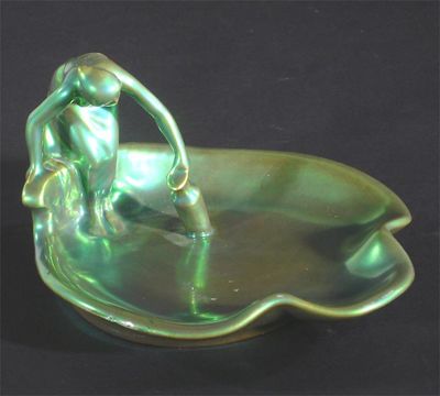 Appraisal: A Zsolnay Pecs figural dish modelled as a woman collecting