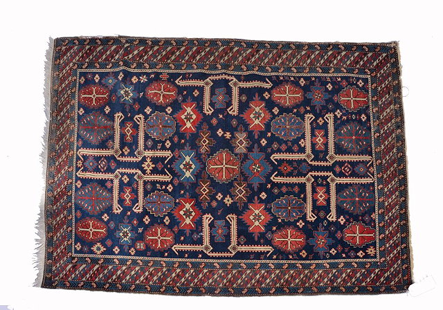 Appraisal: A CAUCASIAN BLUE GROUND RUG with stylised flowerhead designs within