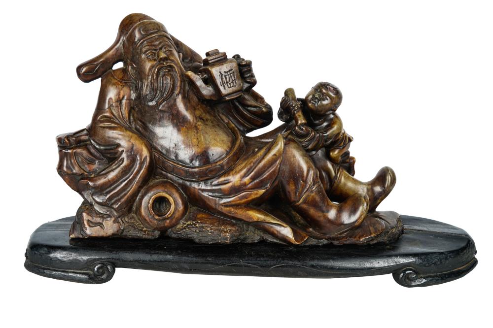 Appraisal: CHINESE CARVED STONE FIGUREdepicted reclining resting on a carved wood