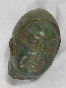 Appraisal: A finely carved green hardstone head with oriental features wearing