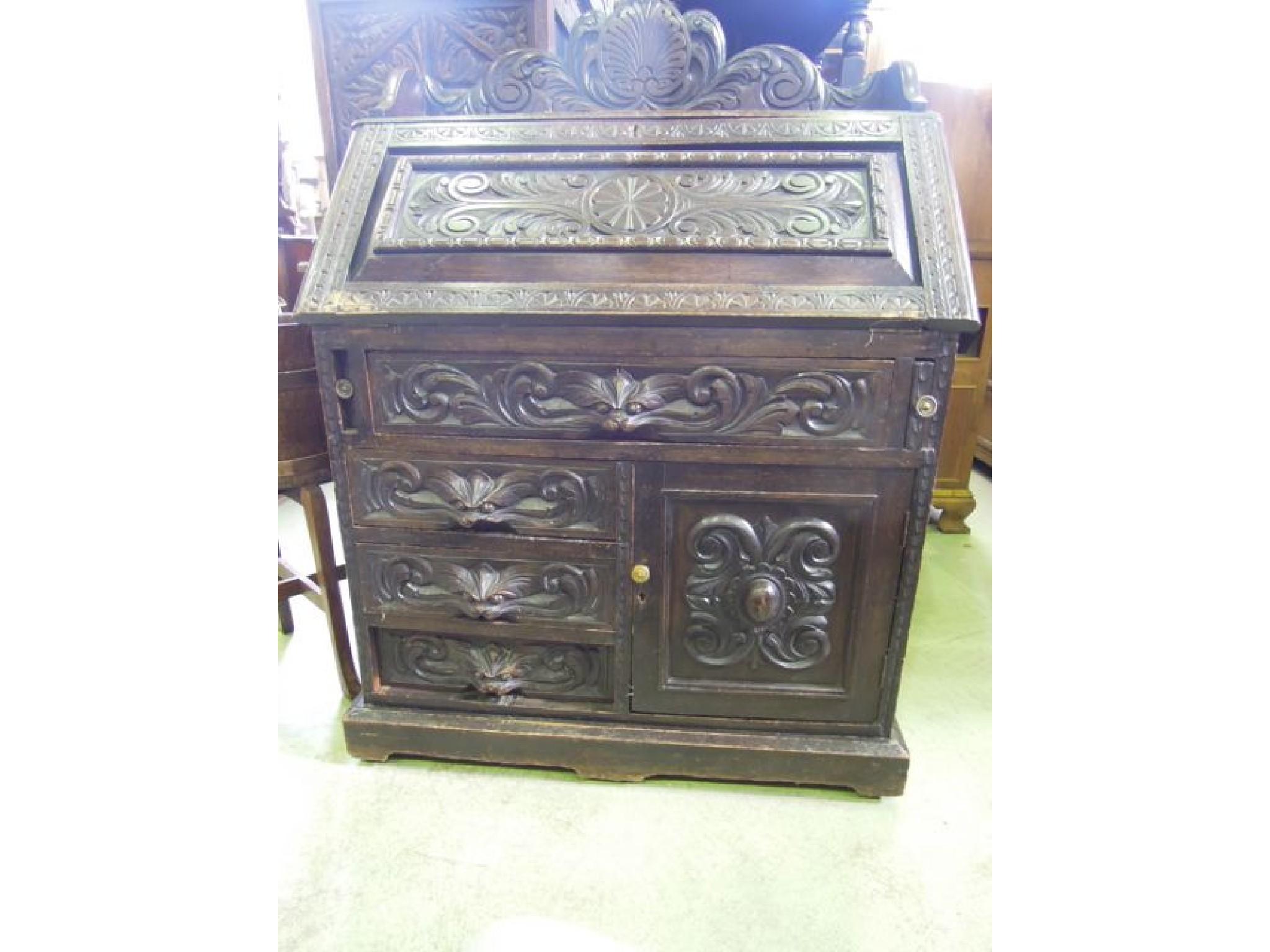 Appraisal: A late Victorian carved oak bureau with raised three quarter