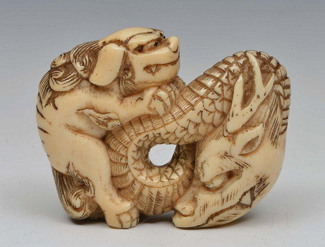 Appraisal: A JAPANESE IVORY NETSUKE dragon and Shishi late Meiji cm