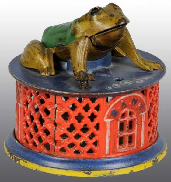 Appraisal: Cast Iron Frog on Lattice Mechanical Bank Description Manufactured by