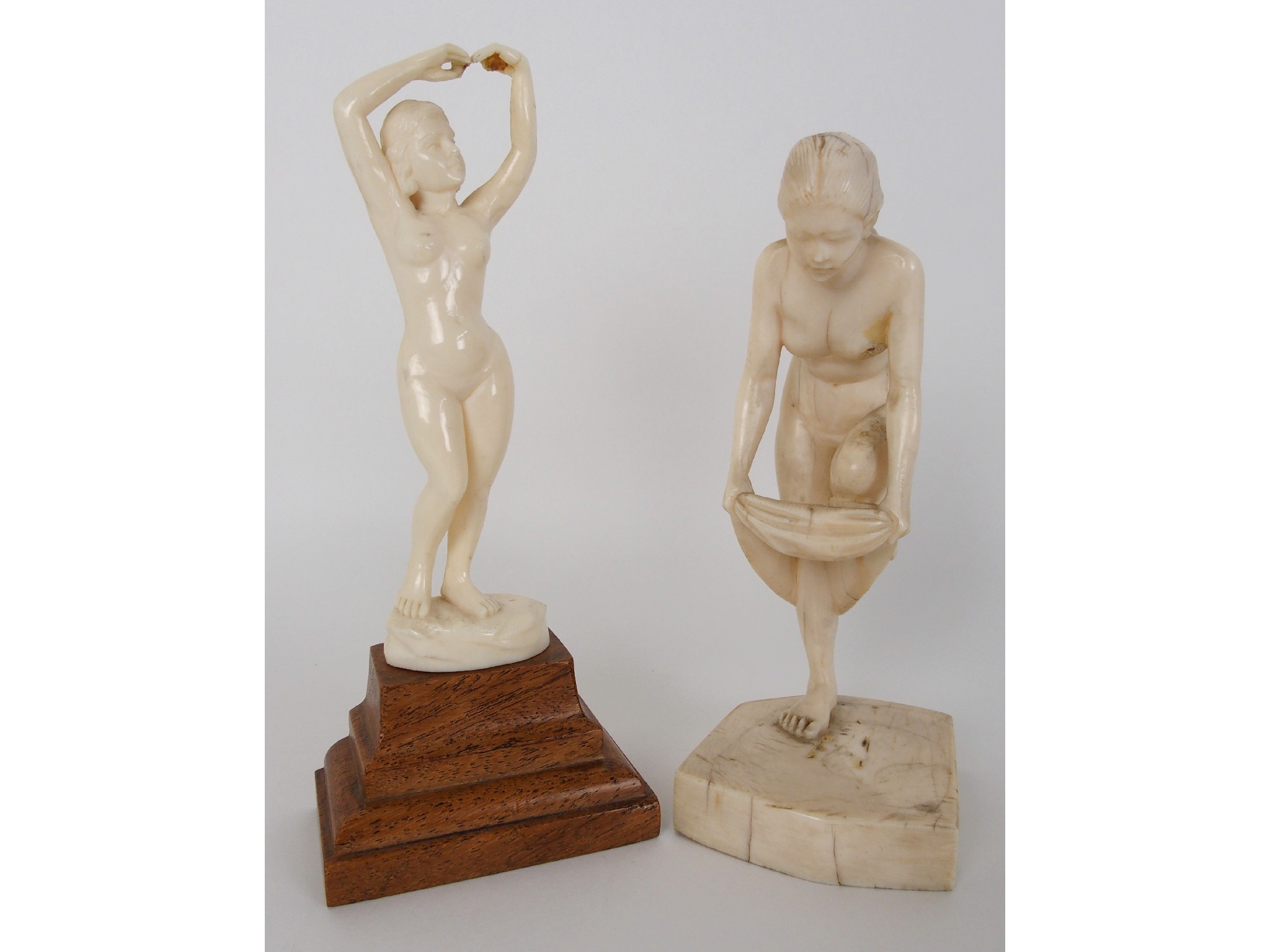 Appraisal: Two carved ivory figures of female nudesone depicted dressing the