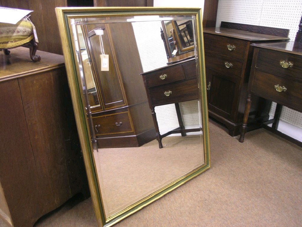 Appraisal: A gilt and green painted mirror with decorative bevelled border