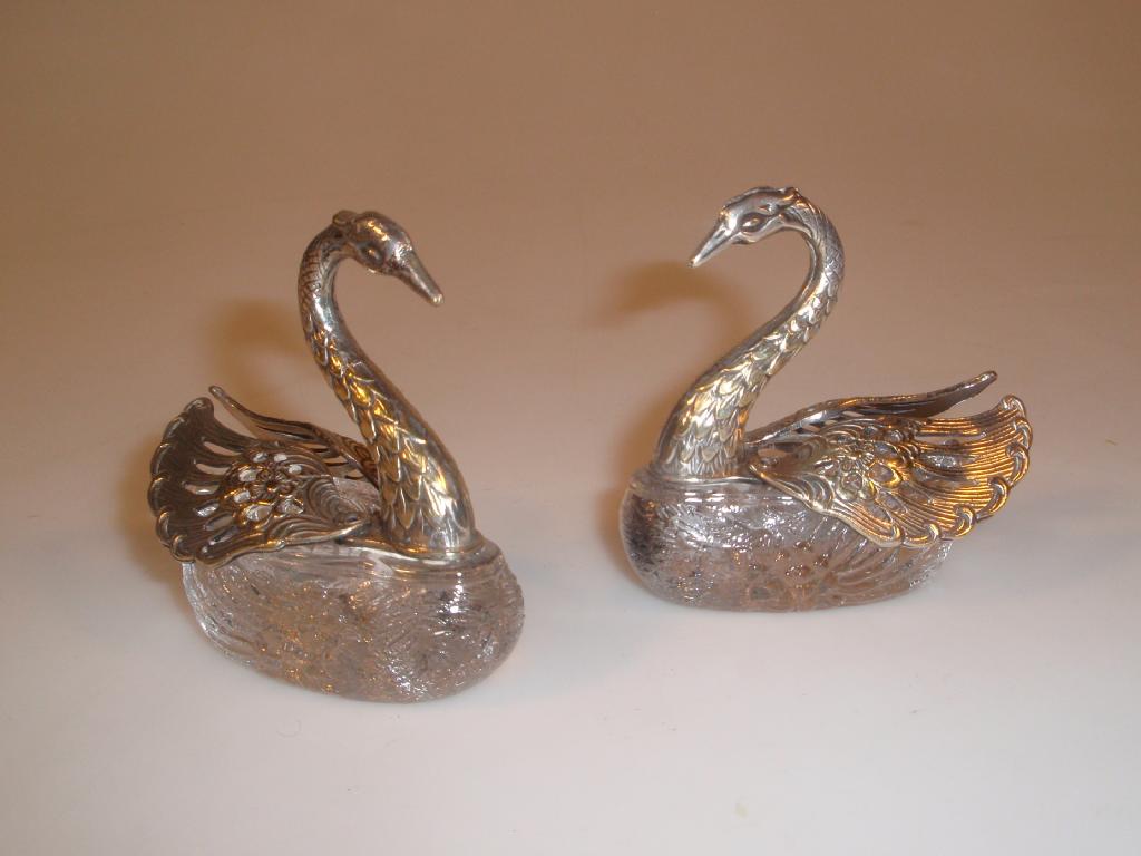 Appraisal: A pair of clear glass moulded swans mounted with electroplated