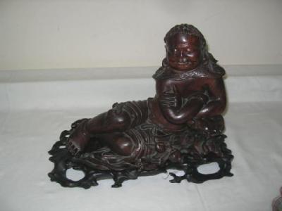 Appraisal: A CHINESE WOOD CARVING modelled as a reclining deity with