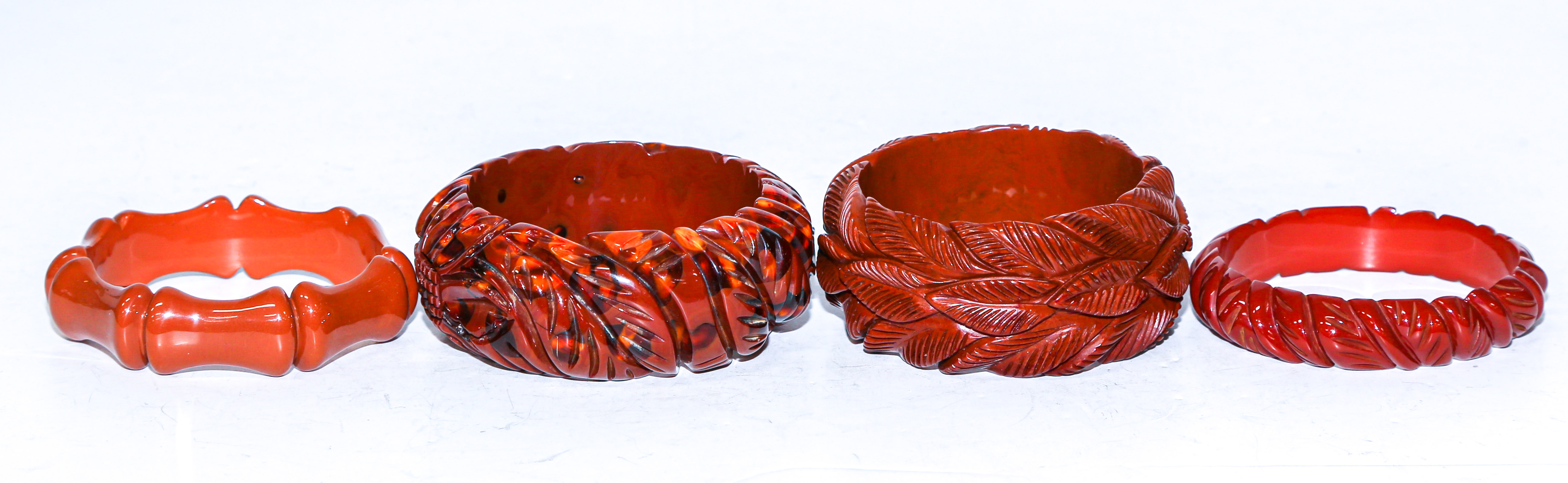 Appraisal: FOUR CARVED ORANGE RED BAKELITE BANGLES Including orange Bakelite bangle