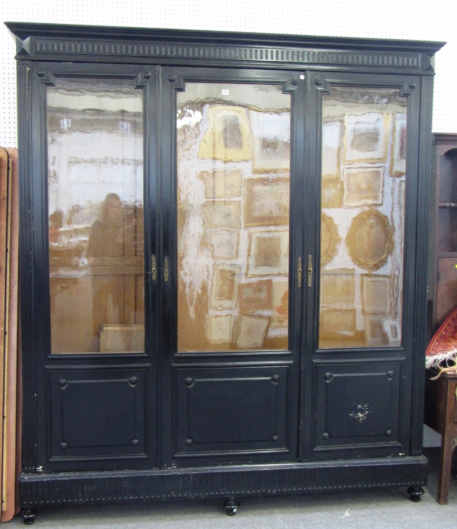 Appraisal: A th century ebonised three door display cabinet on turned