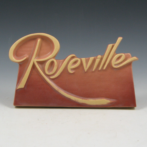 Appraisal: Roseville dealer sign in rose with cream-colored script logo There