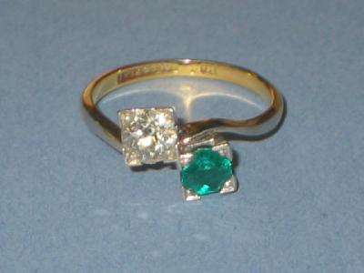 Appraisal: AN EMERALD AND DIAMOND CROSS-OVER RING comprising round cut diamond