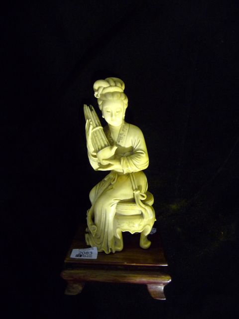 Appraisal: A carved ivory figure of a seated lady holding a