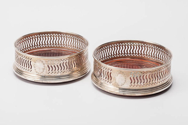 Appraisal: A PAIR OF CIRCULAR WINE BOTTLE COASTERS with pierced silver