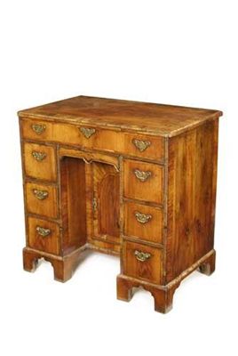 Appraisal: A walnut kneehole desk cross and feather banded the moulded