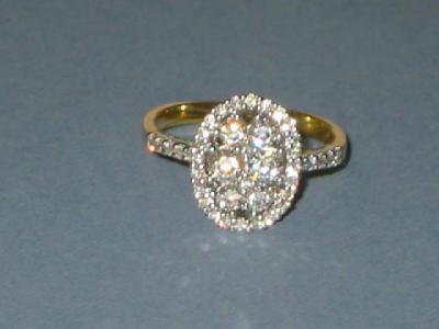 Appraisal: A DIAMOND CLUSTER RING of oval form comprising six brilliant