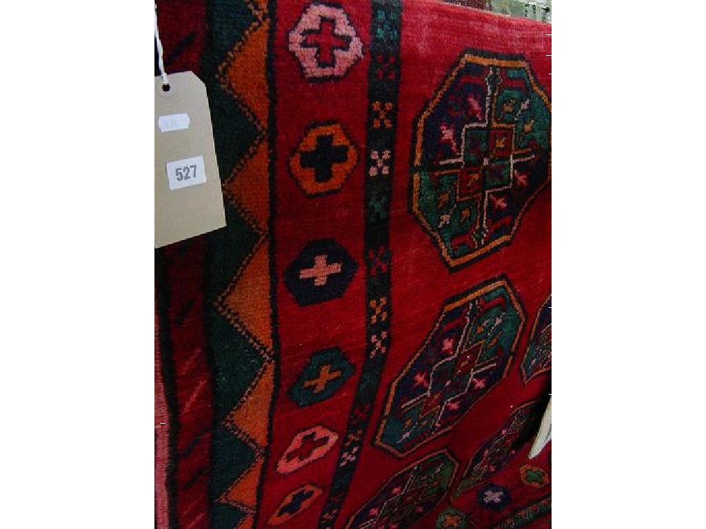 Appraisal: A red ground Eastern wool rug with repeating gul motifs