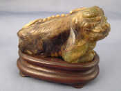 Appraisal: A Chinese variegated green jade recumbent lion on carved hardwood